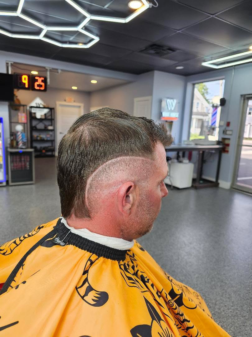 Comb-over with a razored hard part and taper