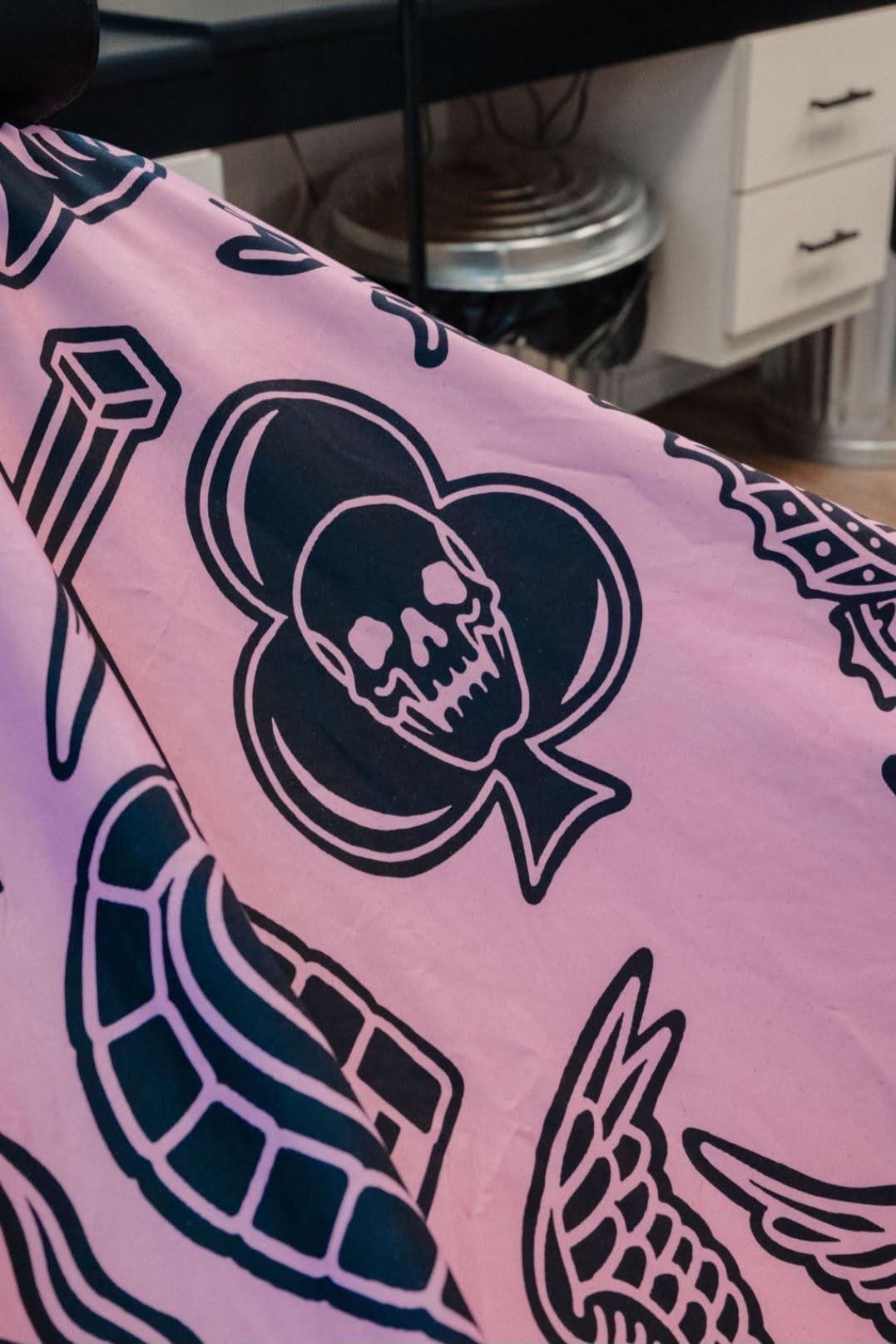 Close-up of the shop's pink tattoo-print barber cape