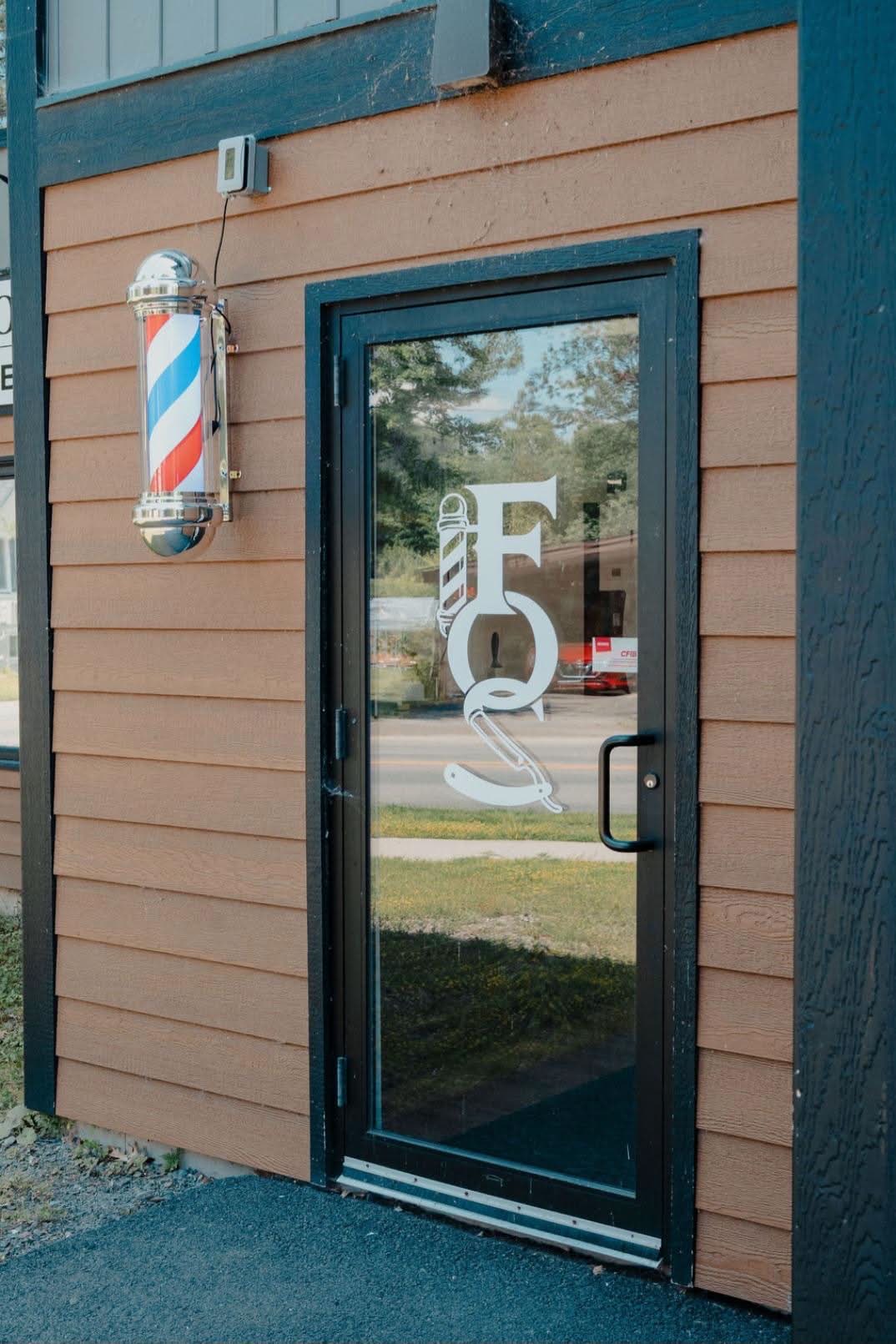 The front door with the shop monogram and the barber pole