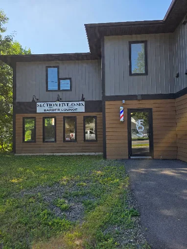 The Section Five-O-Six Barber Lounge building on Greenwood Drive, sign above the windows and barber pole by the door